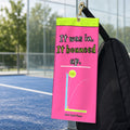 It Was In, It Bounced Up padel court towel hanging from a brass clip on a black padel bag beside a padel court
